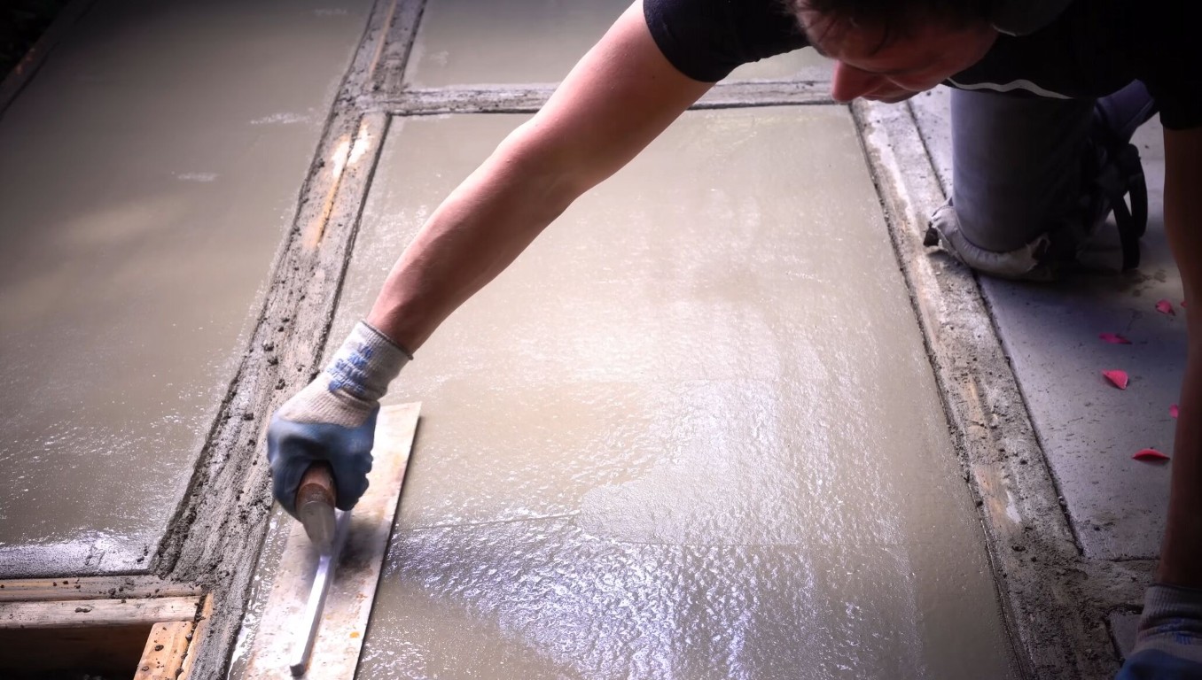 Concrete contractor finishing and smoothing a repaired concrete surface with a trowel