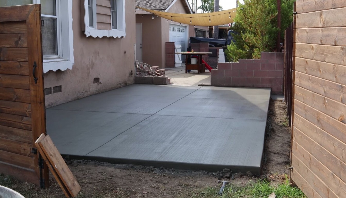 Freshly poured concrete patio in a residential backyard